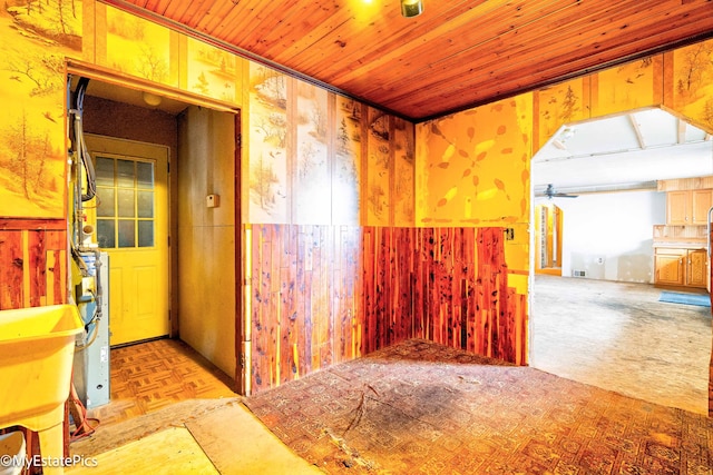 spare room featuring wood walls, wood ceiling, a ceiling fan, and a sink