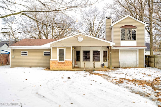 view of front of home featuring an attached garage, a chimney, fence, and brick siding