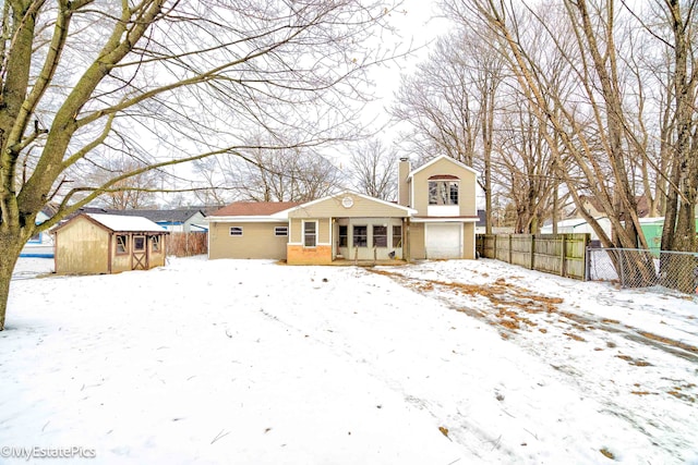 snow covered house with an outbuilding, brick siding, fence, and a chimney