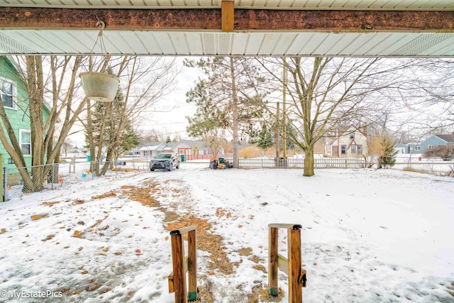 snowy yard featuring a residential view and fence