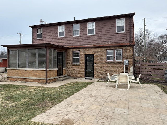 rear view of property with a sunroom, brick siding, and a patio