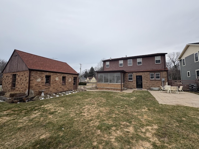 back of property with a sunroom, a patio area, a lawn, and brick siding