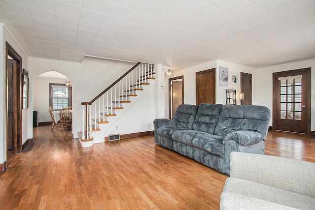 living area featuring baseboards, visible vents, arched walkways, stairway, and wood finished floors