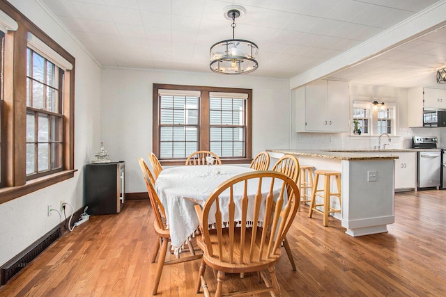 dining space featuring a wealth of natural light, a notable chandelier, crown molding, and wood finished floors