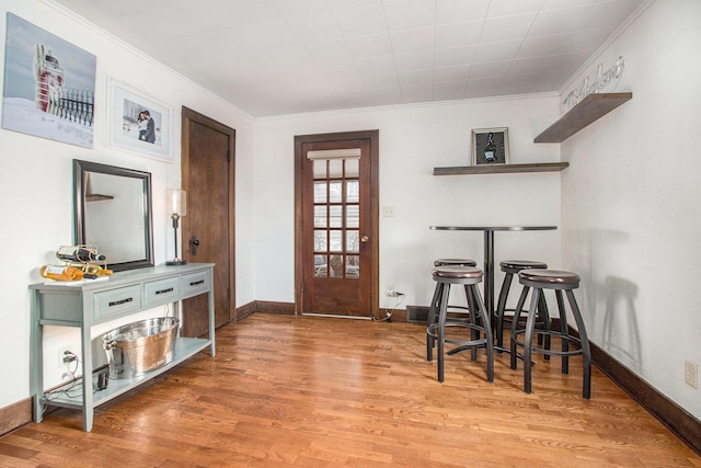 foyer featuring light wood-type flooring, crown molding, and baseboards