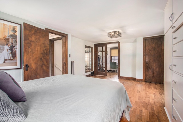 bedroom featuring french doors, baseboards, and wood finished floors