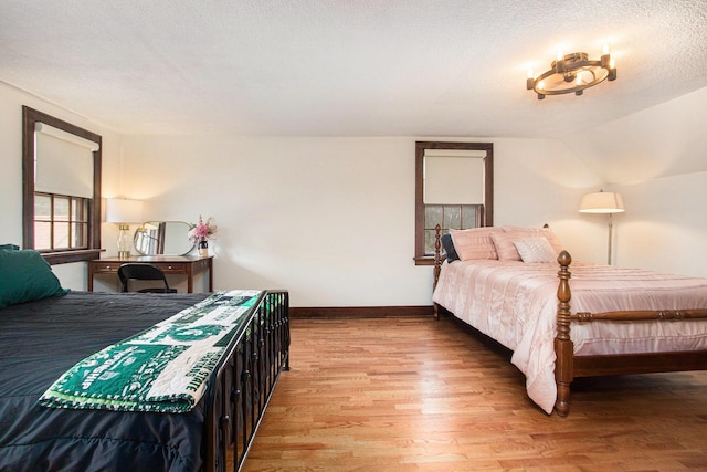 bedroom with a textured ceiling, baseboards, and wood finished floors