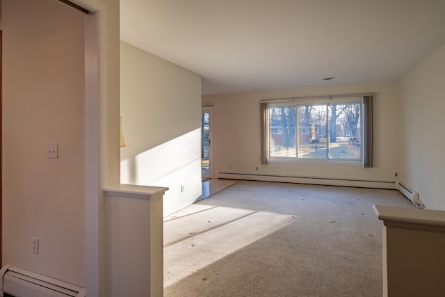 carpeted spare room with a baseboard heating unit