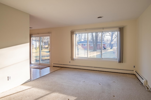 carpeted empty room featuring visible vents, a healthy amount of sunlight, and a baseboard heating unit