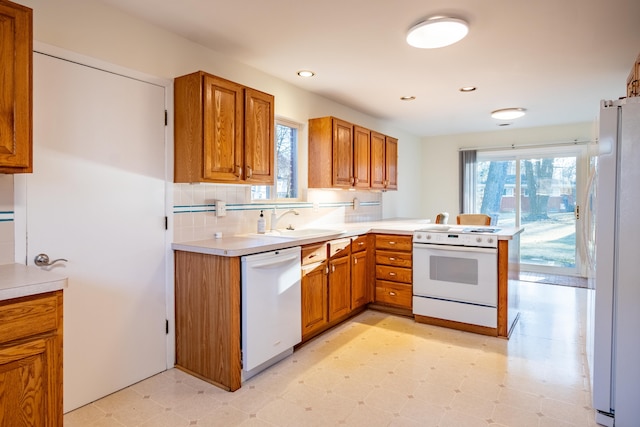 kitchen with a sink, white appliances, light floors, and brown cabinetry