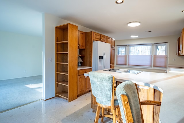 kitchen featuring open shelves, cooktop, light countertops, white fridge with ice dispenser, and brown cabinets