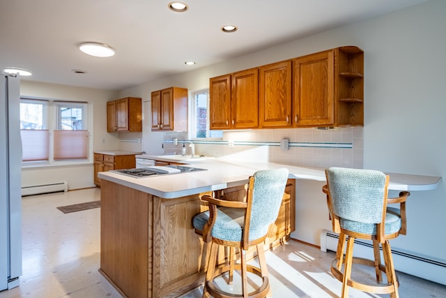 kitchen featuring light floors, light countertops, brown cabinets, a peninsula, and a baseboard radiator