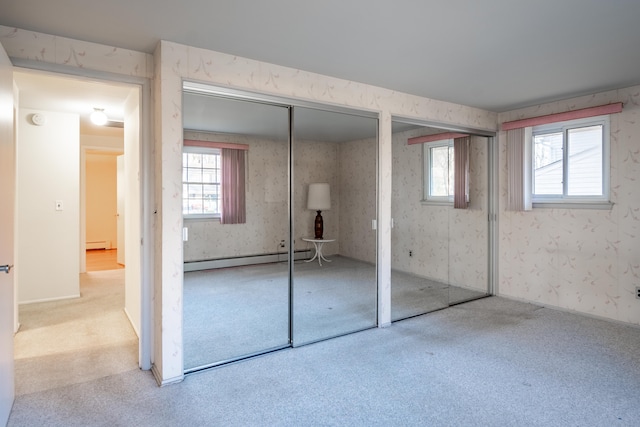 unfurnished bedroom featuring a baseboard heating unit, carpet flooring, two closets, and wallpapered walls