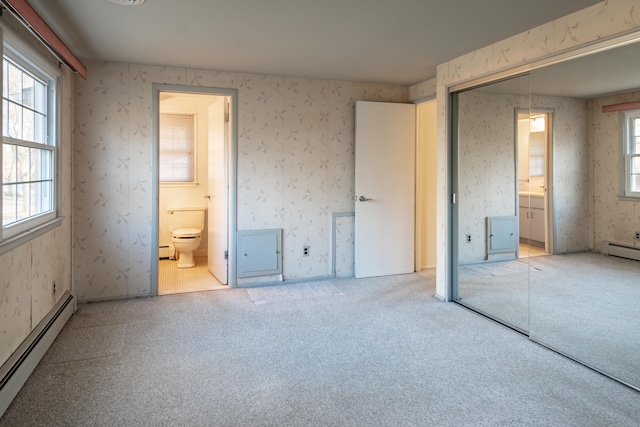 unfurnished bedroom with connected bathroom, carpet floors, baseboard heating, and wallpapered walls