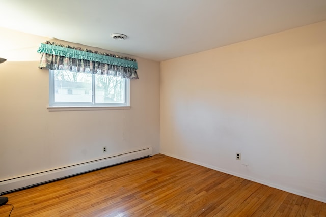 spare room with hardwood / wood-style floors, visible vents, and a baseboard radiator