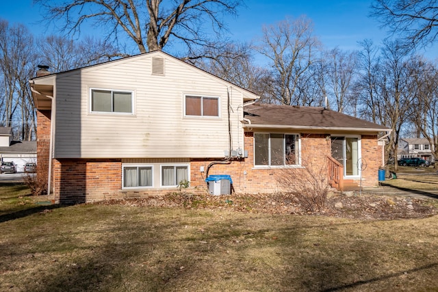 back of house with a lawn, brick siding, and a chimney