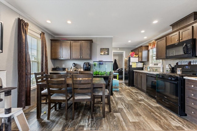 kitchen featuring light countertops, dark wood-type flooring, ornamental molding, dark brown cabinets, and black appliances