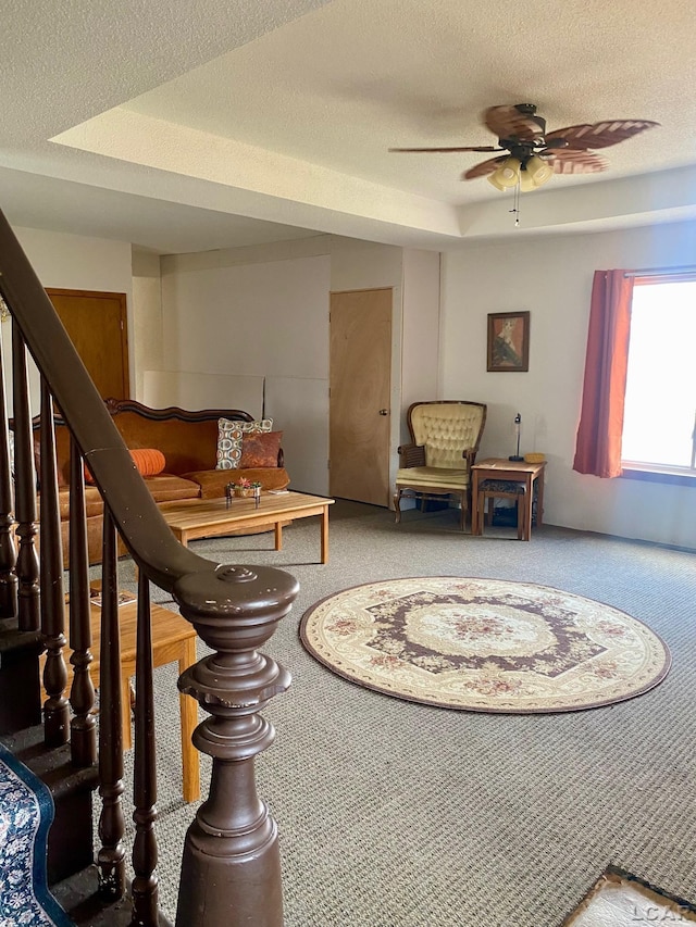 living area featuring stairs, a textured ceiling, and carpet flooring