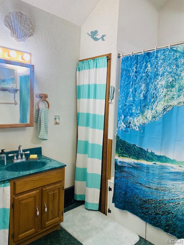 full bath featuring vaulted ceiling, a textured wall, and vanity