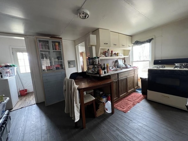 kitchen featuring open shelves, dark wood-type flooring, range with gas cooktop, and washer / dryer