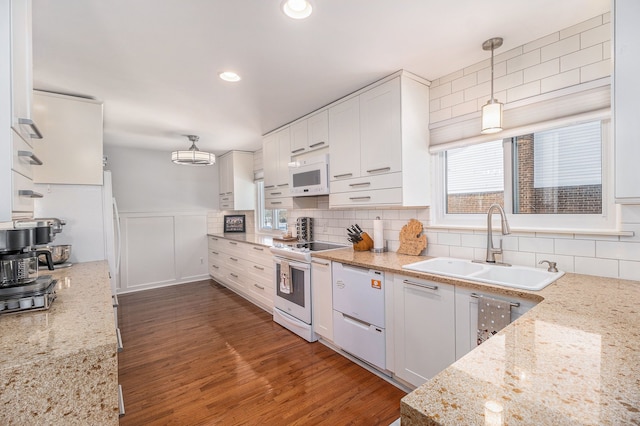 kitchen featuring white appliances, white cabinets, a wainscoted wall, dark wood-type flooring, and a sink