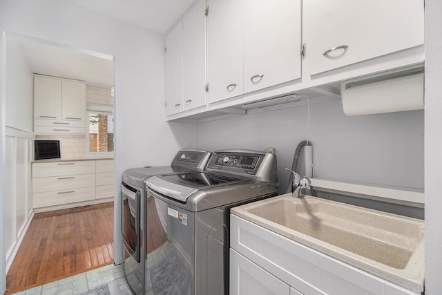 laundry room featuring a sink, light wood-style flooring, washing machine and clothes dryer, and cabinet space