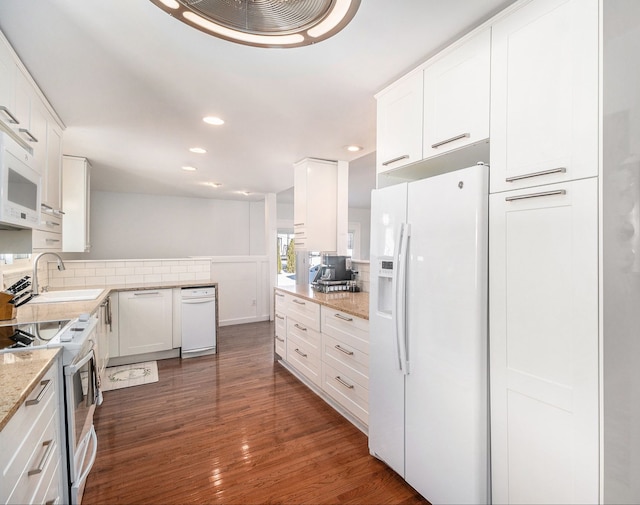 kitchen featuring white appliances, white cabinets, dark wood finished floors, decorative backsplash, and a sink