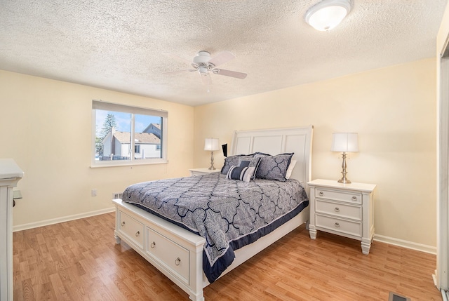 bedroom featuring a ceiling fan, baseboards, a textured ceiling, and light wood finished floors