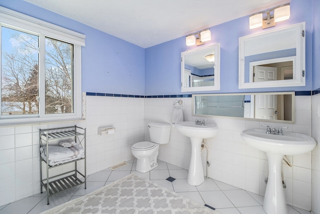 bathroom with tile walls, toilet, and tile patterned floors