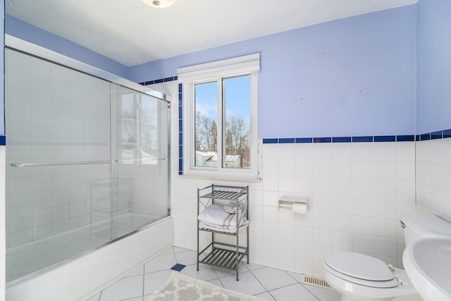 full bath featuring enclosed tub / shower combo, toilet, a sink, tile walls, and tile patterned floors