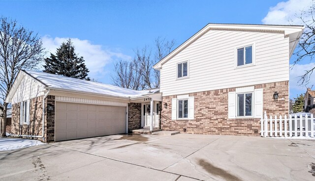 traditional home featuring concrete driveway, brick siding, fence, and an attached garage