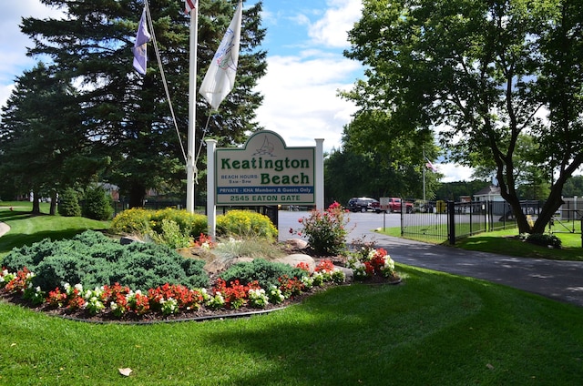 community / neighborhood sign with a yard and fence