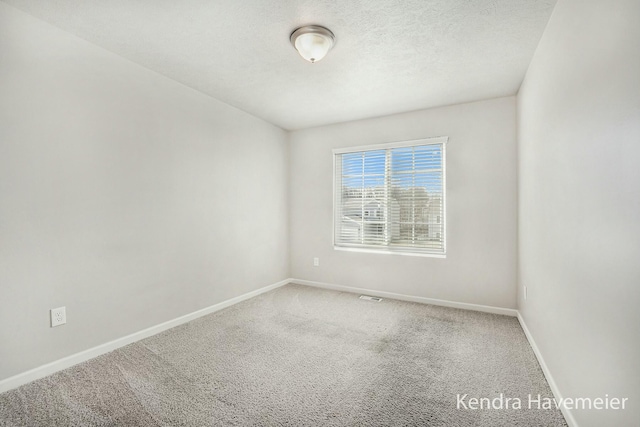 carpeted spare room with a textured ceiling and baseboards