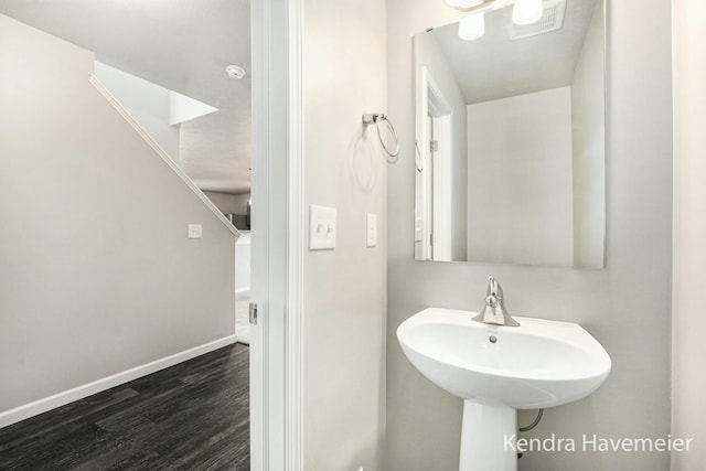 bathroom with a sink, visible vents, baseboards, and wood finished floors