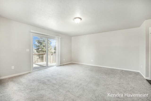 unfurnished room with a textured ceiling, carpet, and baseboards