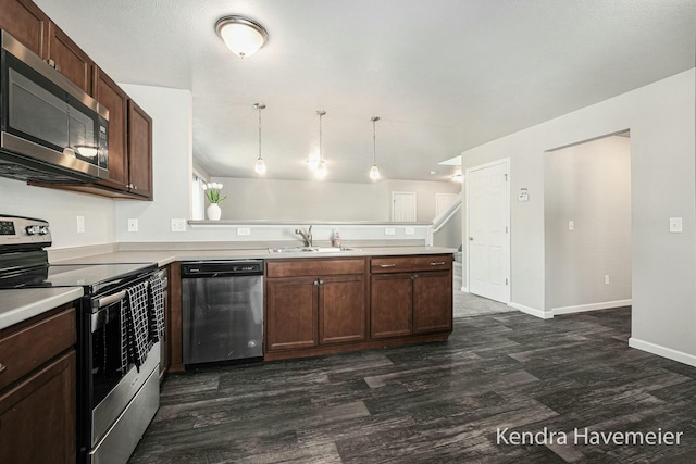 kitchen with a peninsula, appliances with stainless steel finishes, a sink, and light countertops