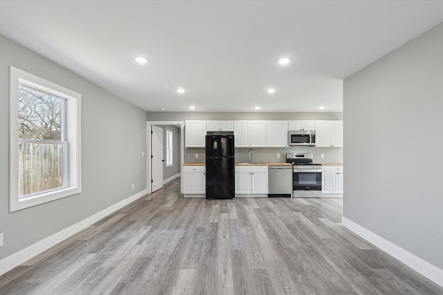 706 Colfax St, Cadillac, MI 49601 - kitchen featuring appliances with stainless steel finishes, a sink, white cabinetry, light wood-style flooring, and recessed lighting