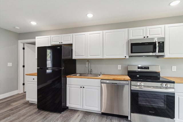 706 Colfax St, Cadillac, MI 49601 - kitchen featuring appliances with stainless steel finishes, wood counters, a sink, white cabinets, and light wood-style floors