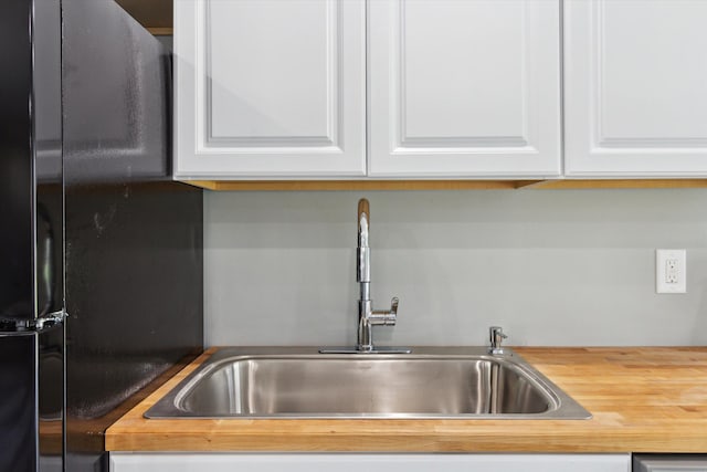 706 Colfax St, Cadillac, MI 49601 - kitchen featuring freestanding refrigerator, a sink, white cabinetry, and butcher block countertops