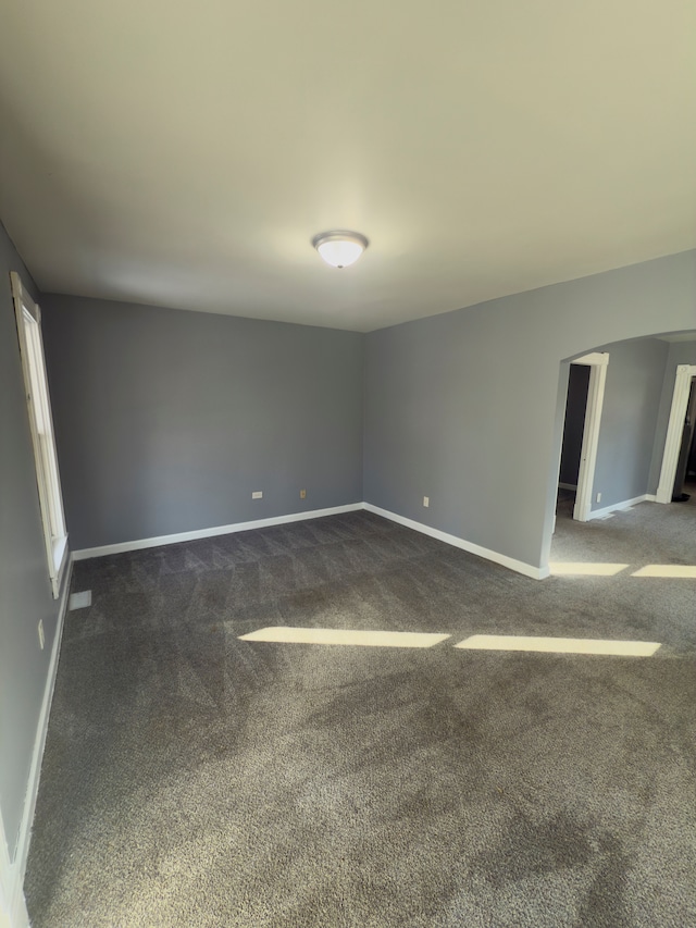 spare room featuring visible vents, baseboards, and dark colored carpet