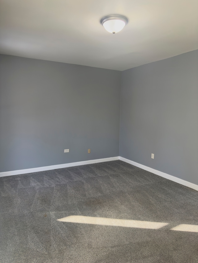 empty room with baseboards and dark colored carpet