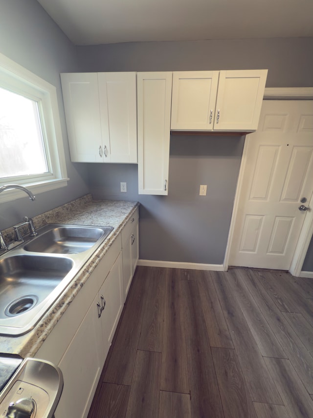 kitchen with a sink, baseboards, dark wood-type flooring, and white cabinets