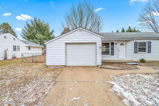 ranch-style home featuring concrete driveway, roof with shingles, an attached garage, and fence