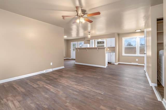 unfurnished living room featuring visible vents, dark wood-type flooring, a ceiling fan, and baseboards