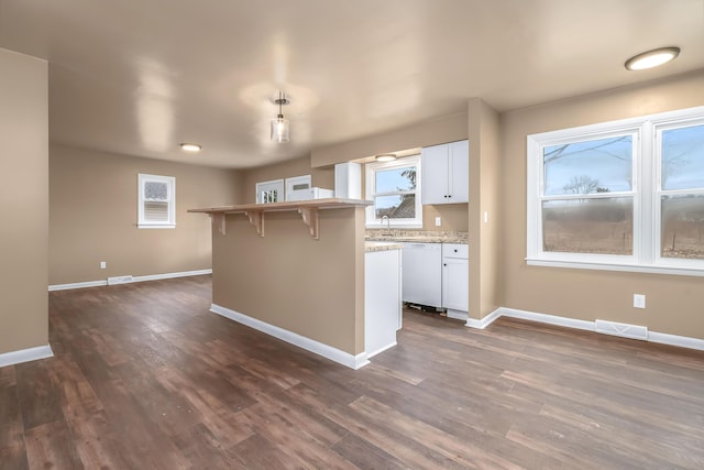 kitchen with white dishwasher, visible vents, baseboards, white cabinets, and dark wood finished floors