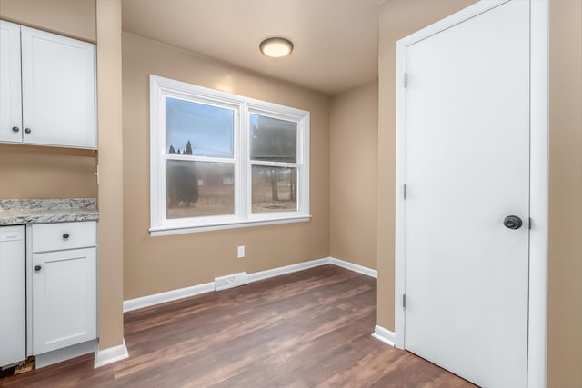 unfurnished dining area with baseboards, visible vents, and dark wood-type flooring