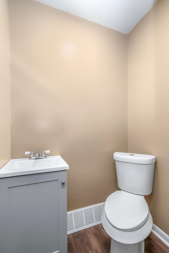 bathroom featuring toilet, visible vents, wood finished floors, and vanity