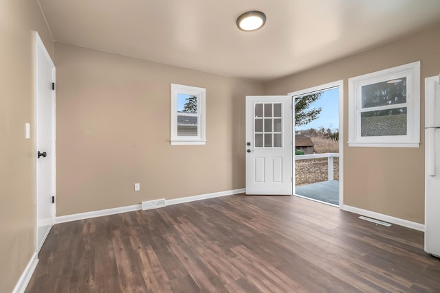 interior space with baseboards, visible vents, and dark wood-type flooring