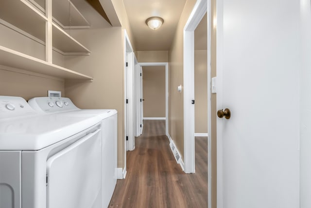 clothes washing area with dark wood-type flooring, laundry area, independent washer and dryer, and baseboards