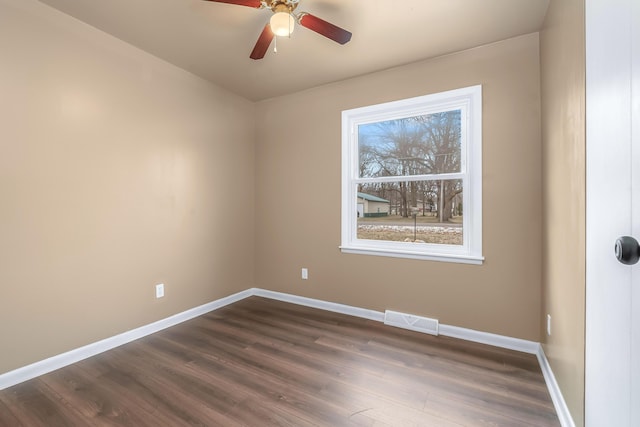 spare room featuring dark wood-style floors, ceiling fan, visible vents, and baseboards